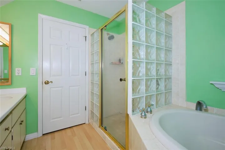 Bathroom with independent shower and bath, vanity, and hardwood / wood-style flooring