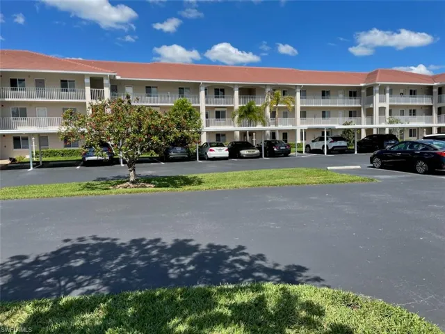 View of apartment building / complex featuring uncovered parking