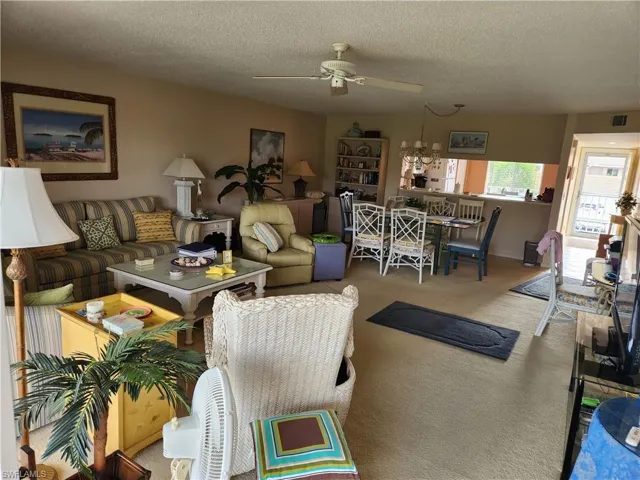 Carpeted living room with a ceiling fan and a textured ceiling