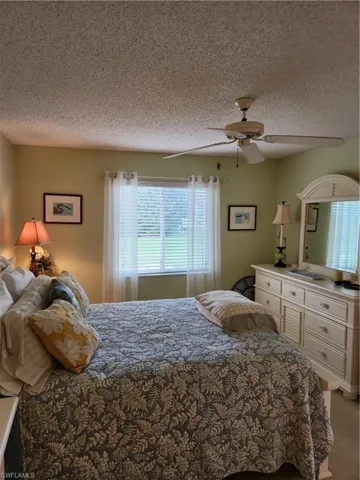 Bedroom with a textured ceiling, light carpet, and a ceiling fan