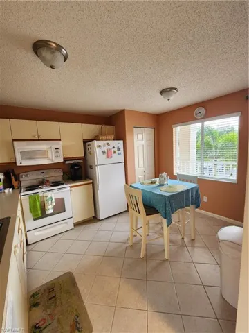 Kitchen featuring range, freestanding refrigerator, a textured ceiling, light tile patterned floors, and light countertops