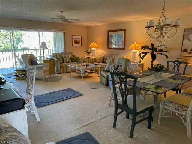 Dining space with light carpet, a textured ceiling, a chandelier, and a ceiling fan