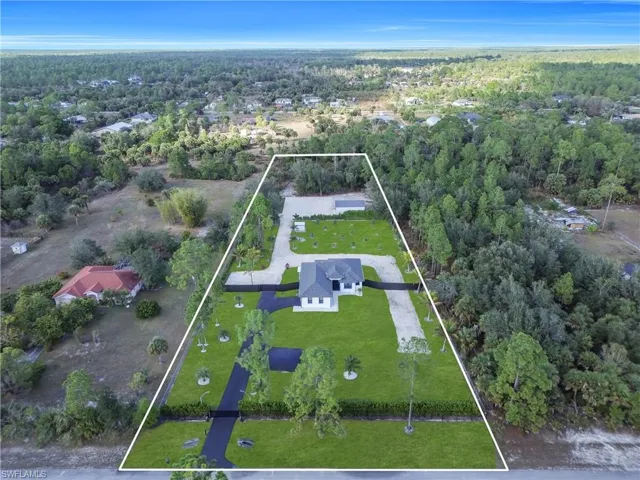 Aerial view of property and surrounding area with property parcel outlined and a heavily wooded area