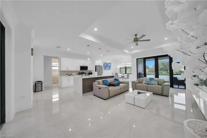 Living area featuring a raised ceiling, ceiling fan, and recessed lighting