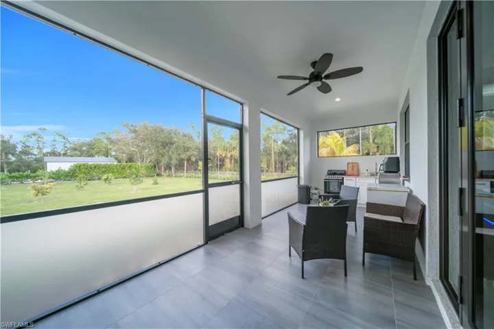 Sunroom with an outdoor kitchen, ceiling fan, and an outdoor living space