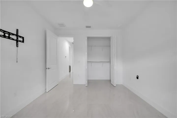 Unfurnished bedroom with ceiling fan, a closet, and light marble finish floors