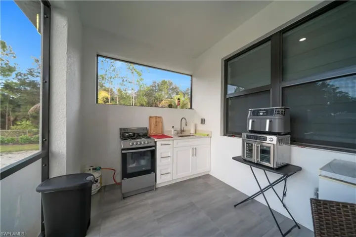 Kitchen featuring stainless steel range with gas cooktop, white cabinets, light countertops, healthy amount of natural light, and a textured wall
