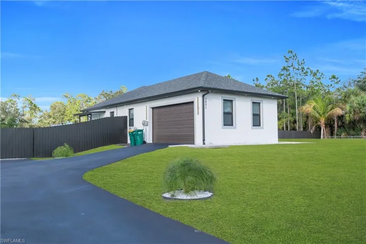 View of side of property with stucco siding, asphalt driveway, a garage, and roof with shingles