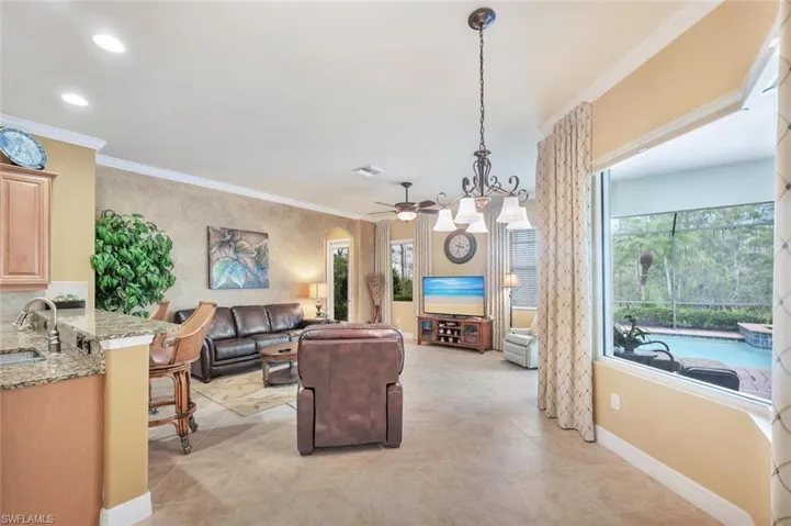 Living area with ornamental molding, a ceiling fan, arched walkways, light tile patterned floors, and recessed lighting
