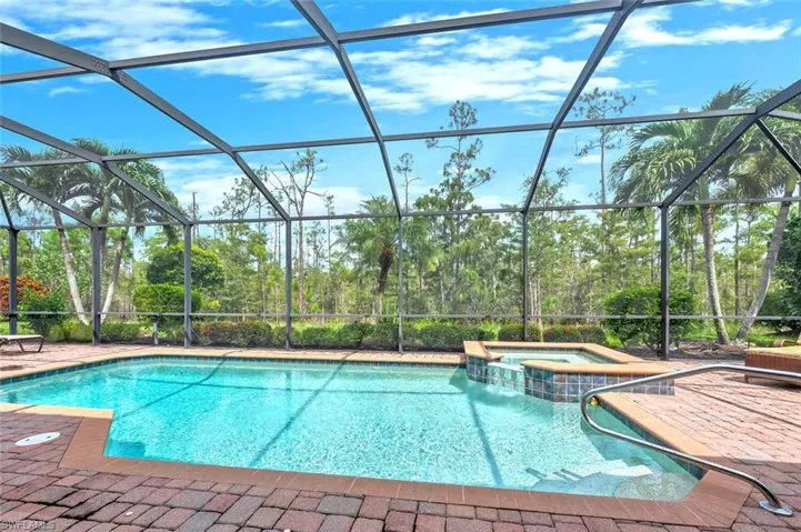 View of swimming pool with a sunroom, a pool with connected hot tub, glass enclosure, and a patio