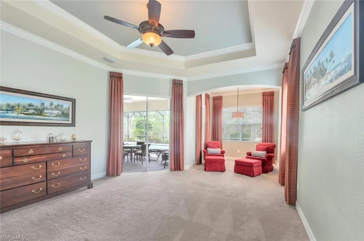 Living area featuring crown molding, a raised ceiling, light carpet, and ceiling fan