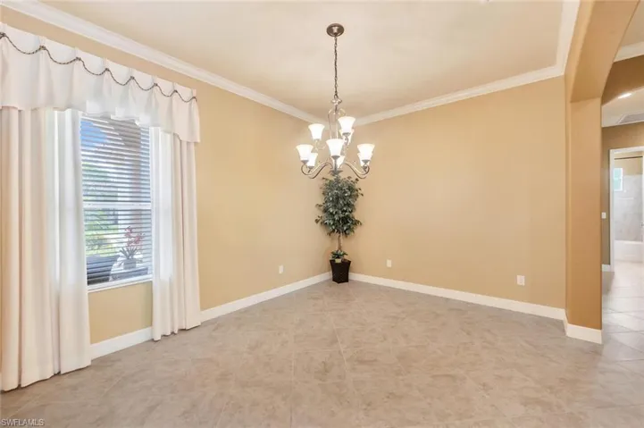 Unfurnished dining area featuring crown molding, light tile patterned floors, and a chandelier