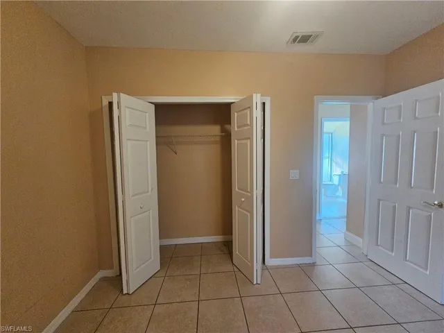 Unfurnished bedroom featuring a closet, visible vents, baseboards, and light tile patterned floors