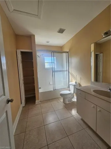 Full bath with visible vents, toilet, combined bath / shower with glass door, vanity, and tile patterned flooring