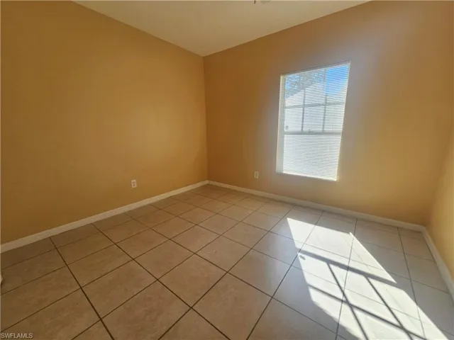 Unfurnished room featuring light tile patterned floors and baseboards