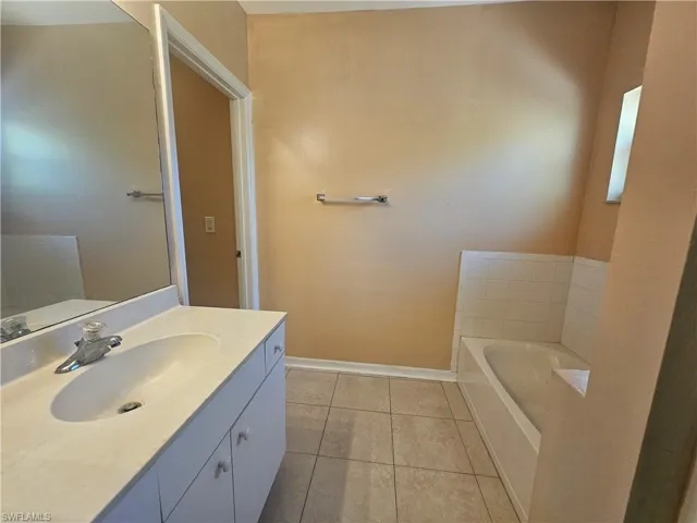 Bathroom with tile patterned flooring, a garden tub, vanity, and baseboards