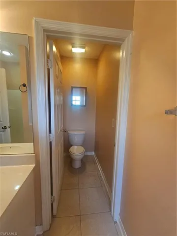 Bathroom with baseboards, vanity, toilet, and tile patterned floors