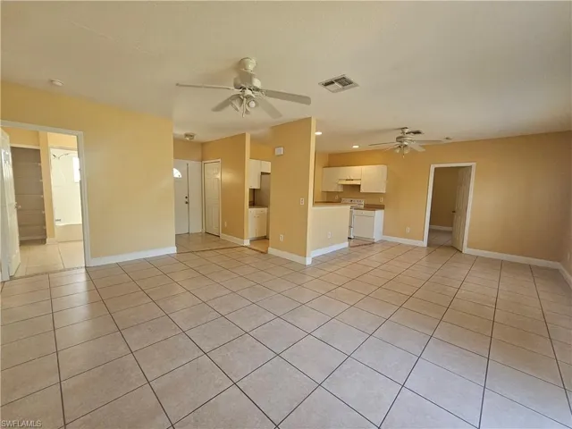 Unfurnished living room featuring visible vents, ceiling fan, baseboards, and light tile patterned floors