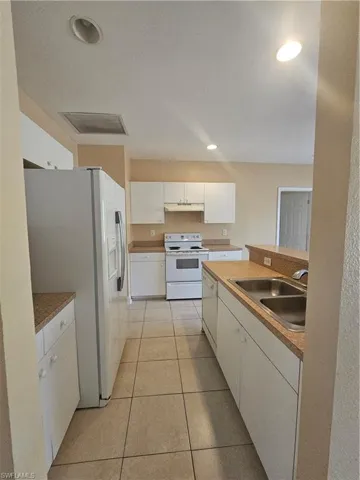 Kitchen featuring range hood, electric range, a sink, dishwashing machine, and fridge