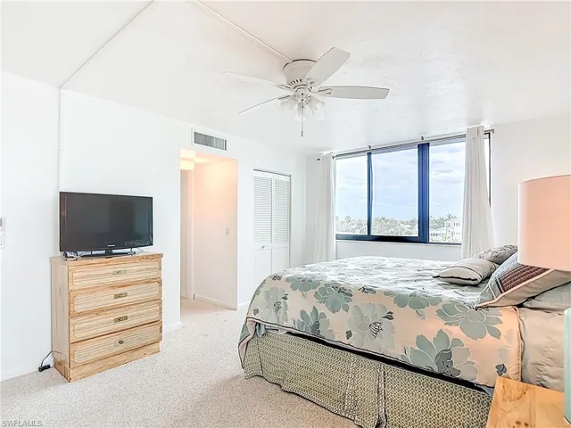Bedroom featuring light colored carpet, a closet, and a ceiling fan