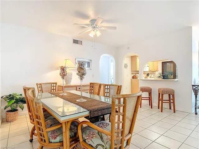 Dining room with light tile patterned flooring, arched walkways, and ceiling fan