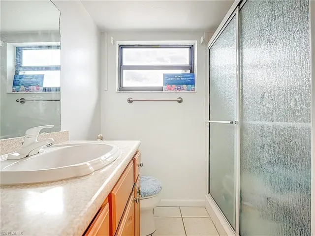 Full bathroom with vanity, light tile patterned floors, and a stall shower