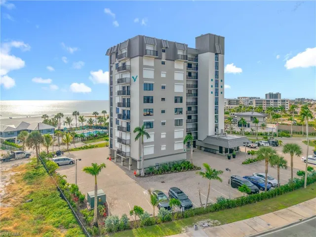 View of building / complex with view of water and beach and uncovered parking