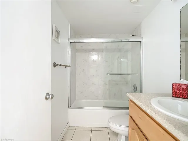 Bathroom featuring vanity, bath / shower combo with glass door, and light tile patterned flooring