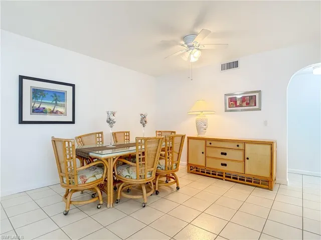 Dining area with arched walkways, light tile patterned floors, and a ceiling fan