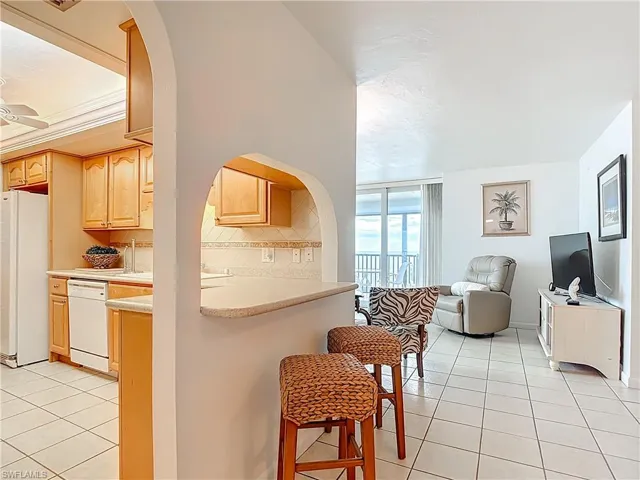 Kitchen featuring white appliances, tasteful backsplash, a breakfast bar, and light tile patterned floors
