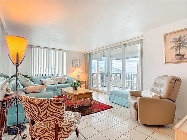 Living room with light tile patterned floors, floor to ceiling windows, healthy amount of natural light, and a textured ceiling