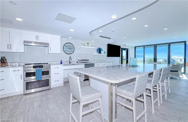 CLUBROOM Kitchen featuring stainless steel appliances, white cabinetry, light stone counters, under cabinet range hood, and recessed lighting