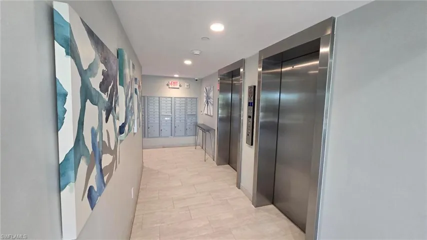 Hallway with elevator, recessed lighting, and mail area
