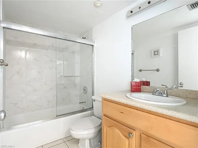 Full bath featuring combined bath / shower with glass door, light tile patterned floors, and vanity