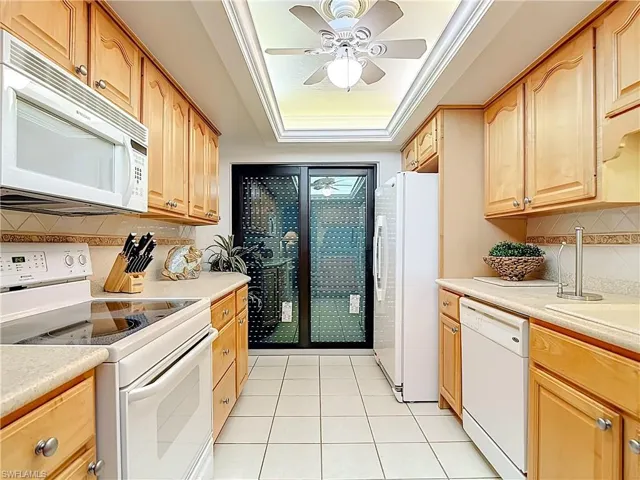 Kitchen featuring tasteful backsplash, white appliances, light tile patterned floors, ornamental molding, and a ceiling fan
