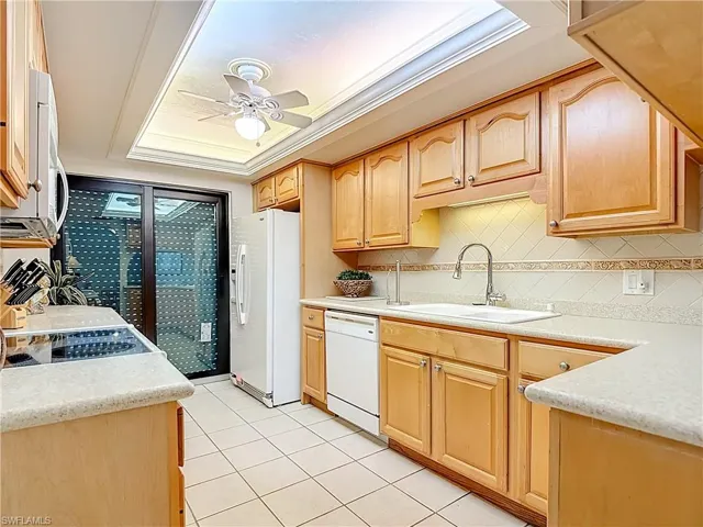 Kitchen featuring backsplash, white appliances, ornamental molding, light tile patterned floors, and ceiling fan