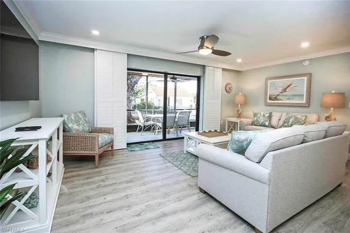 Living room featuring light wood- LVP flooring, ceiling fan, and crown molding