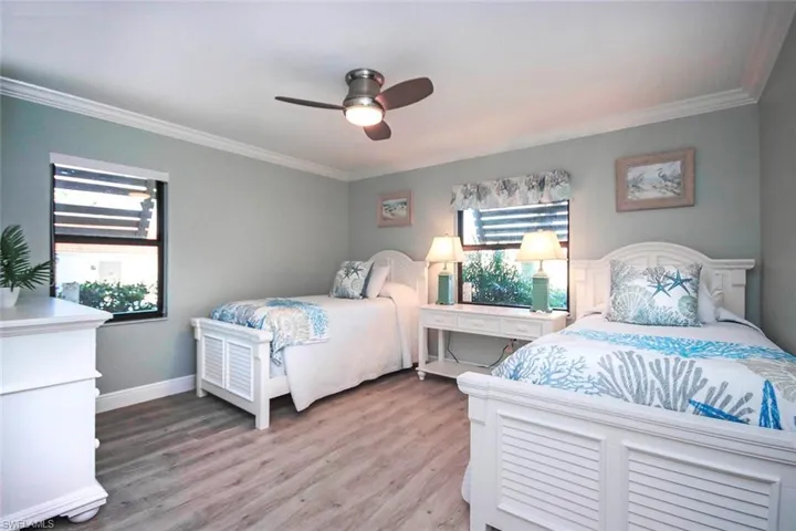 Bedroom with light wood-LVP flooring, ceiling fan, and ornamental molding
