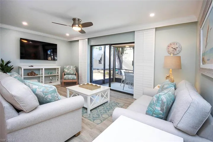 Living room with ceiling fan, light wood-LVP flooring, and crown molding