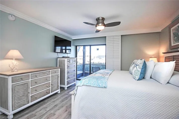 Bedroom featuring wood-LVP flooring, ceiling fan, access to exterior, and ornamental molding