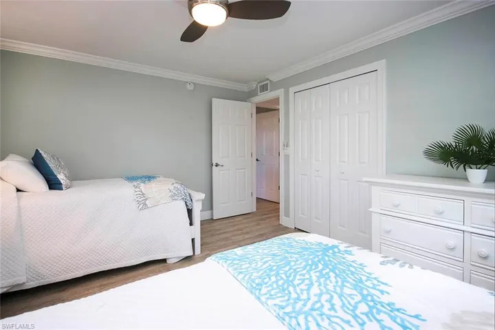 Bedroom featuring wood-LVP flooring, a closet, ceiling fan, and ornamental molding