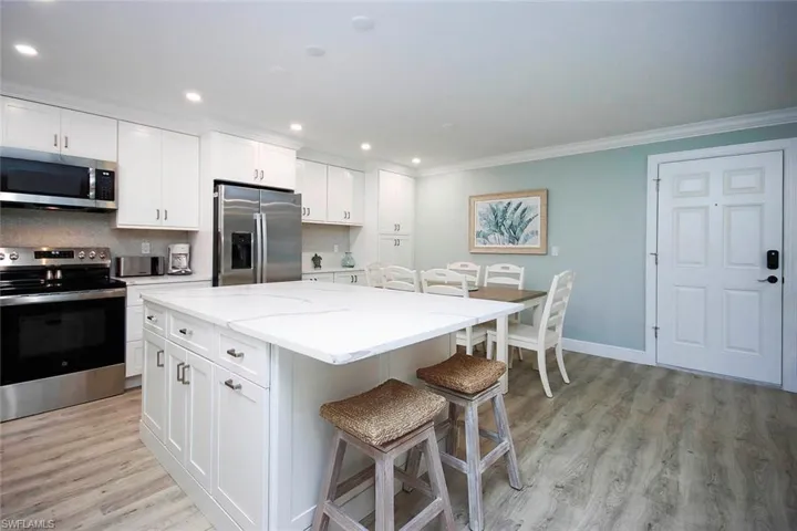 Kitchen with light Quartz countertops, stainless steel appliances, a kitchen island, and white cabinetry