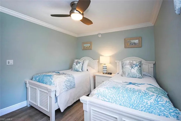 Bedroom with ceiling fan, light wood-LTV flooring, and ornamental molding