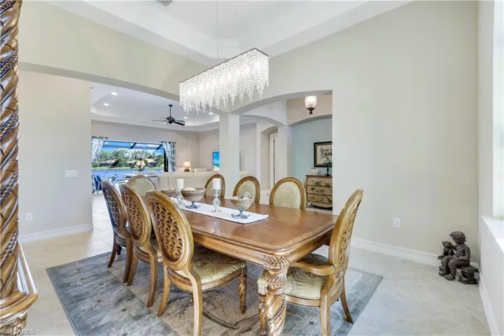 Dining space with ceiling fan, arched walkways, a chandelier, recessed lighting, and a towering ceiling