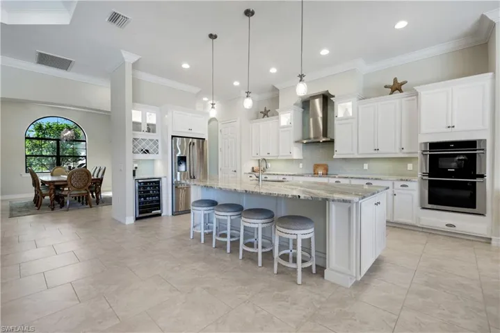 Kitchen featuring backsplash, a kitchen breakfast bar, glass insert cabinets, stainless steel appliances, and light stone counters
