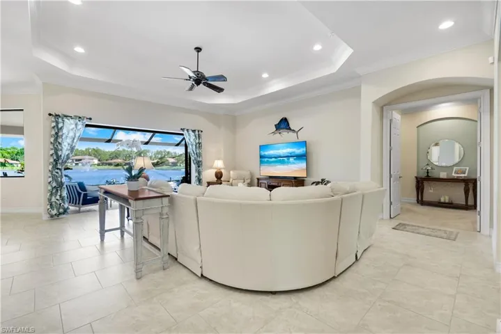 Living area with a tray ceiling, a ceiling fan, recessed lighting, crown molding, and a sunroom