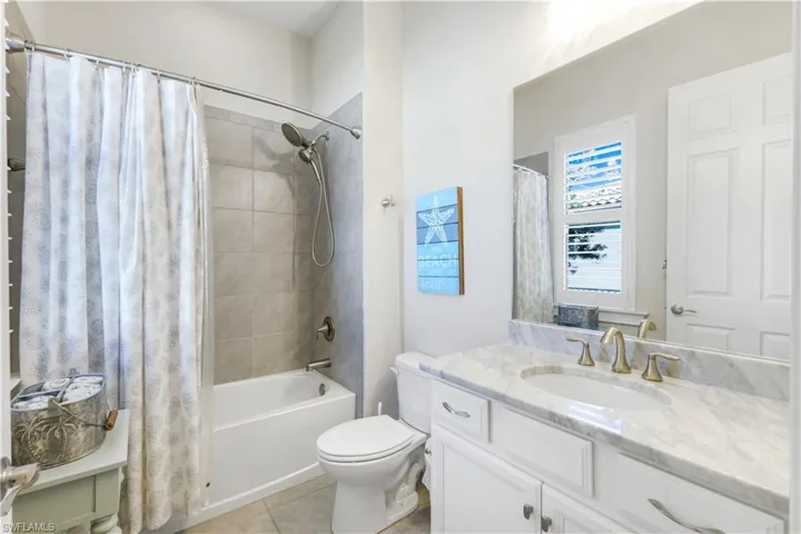 Bathroom with shower / bathtub combination with curtain, vanity, and light tile patterned floors