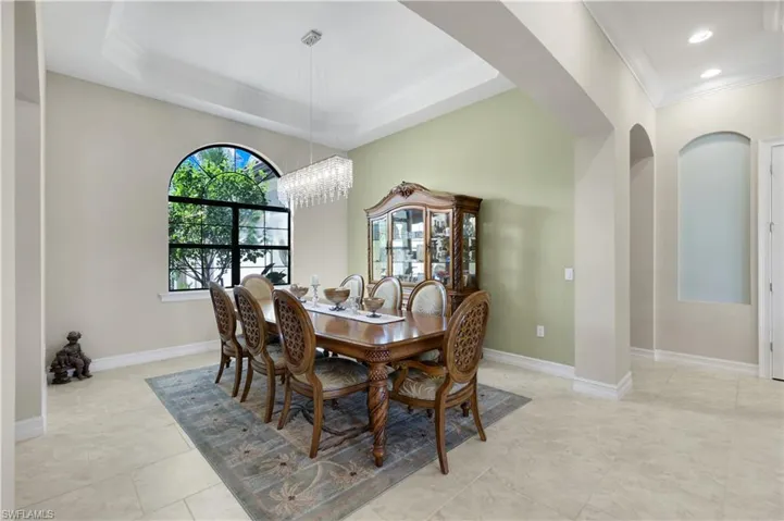 Dining room featuring ornamental molding, arched walkways, a chandelier, and light tile patterned flooring