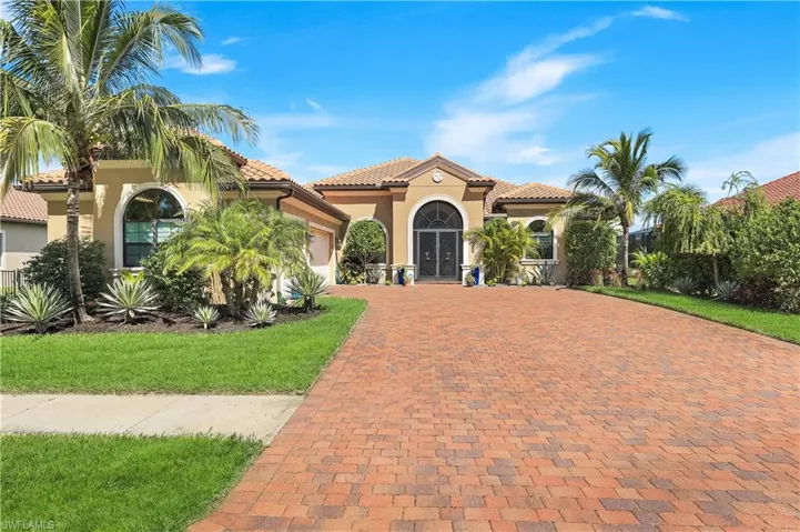 Mediterranean / spanish home featuring stucco siding, decorative driveway, an attached garage, a front yard, and a tiled roof