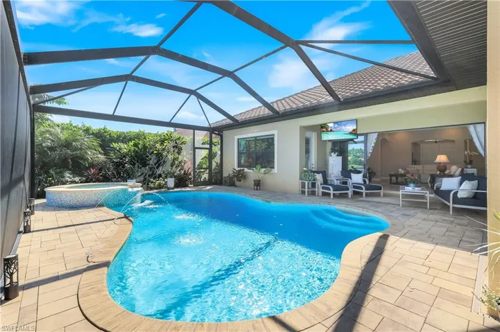 View of pool featuring a patio, glass enclosure, a sunroom, and a pool with connected hot tub